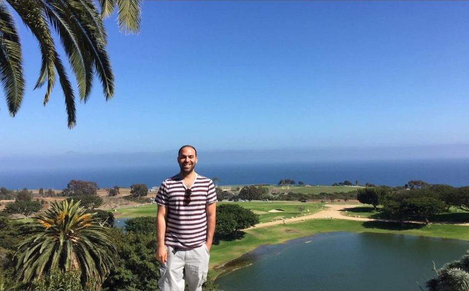 Yaniv Hamudot at a coastal golf overlook, the ocean behind him